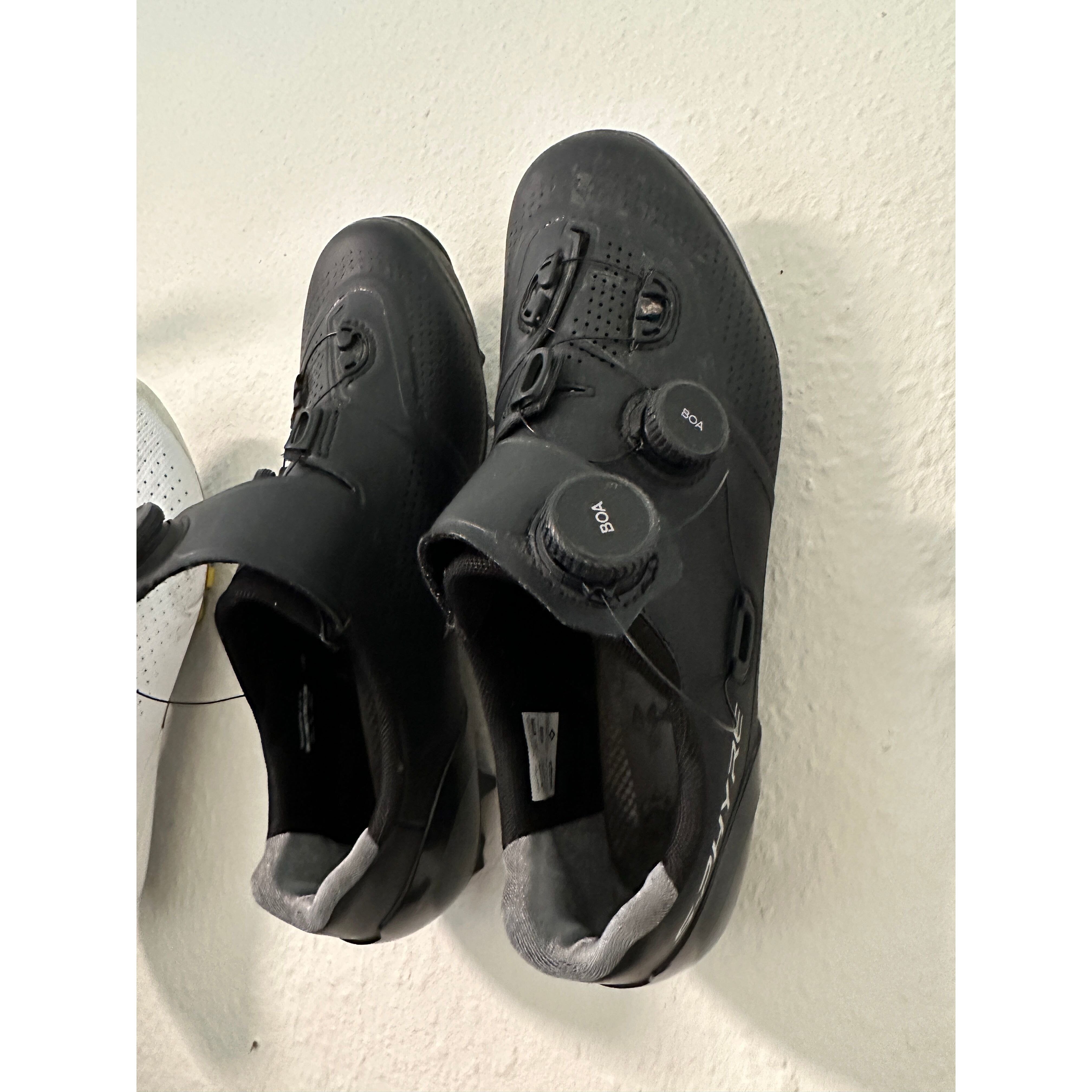 Pair of black road cycling shoes stored on wall mounted shoe holders