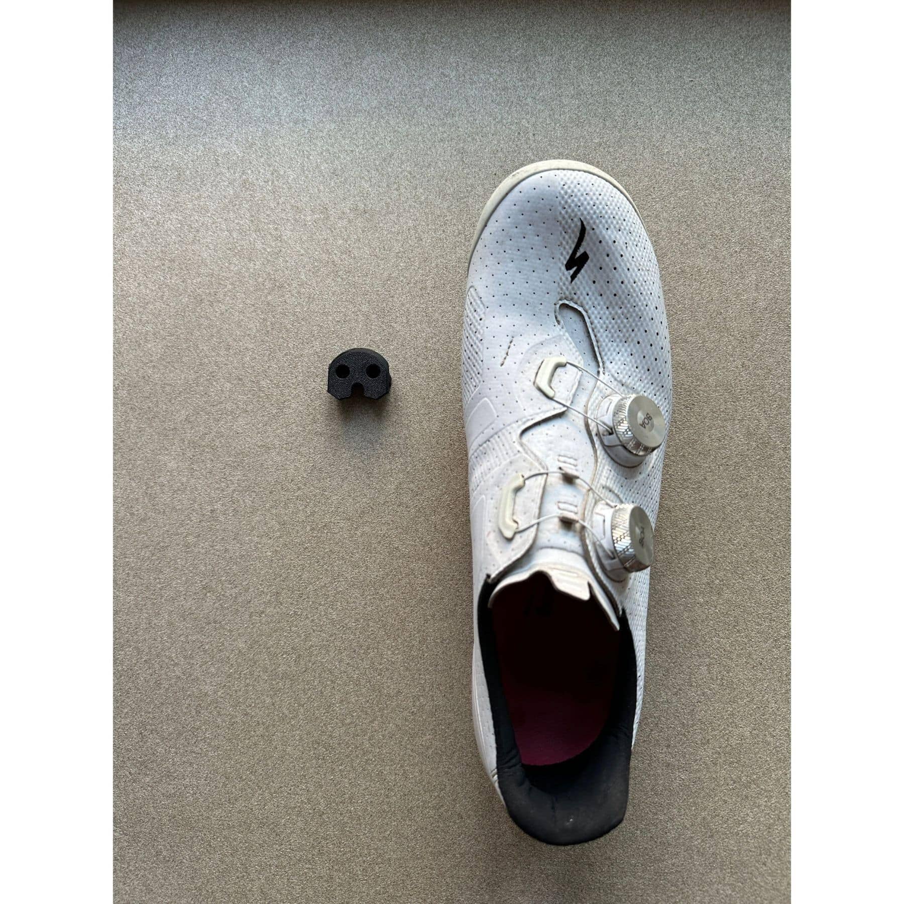 White road cycling shoe next to wall mounted shoe holder for cleat storage